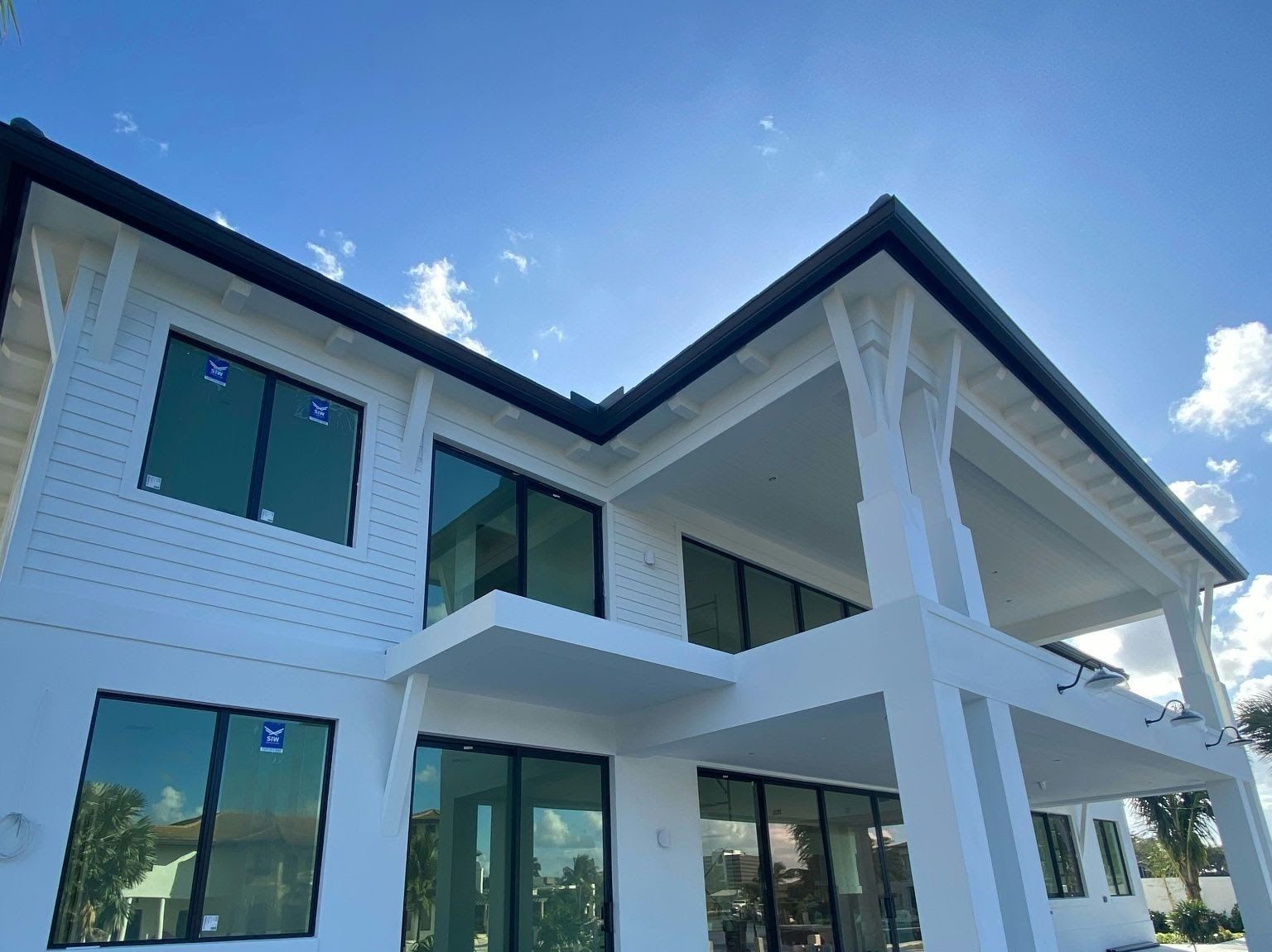Two-story white modern home with new siding, black-framed windows and a covered patio